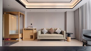 A modern living room with a sofa, a coffee table, and a side table. There is a wardrobe with a mirror and a shoe rack. The room has a ceiling with recessed lighting. - Hilton Garden Inn Beijing Temple of Heaven East Gate Station (Beijing)