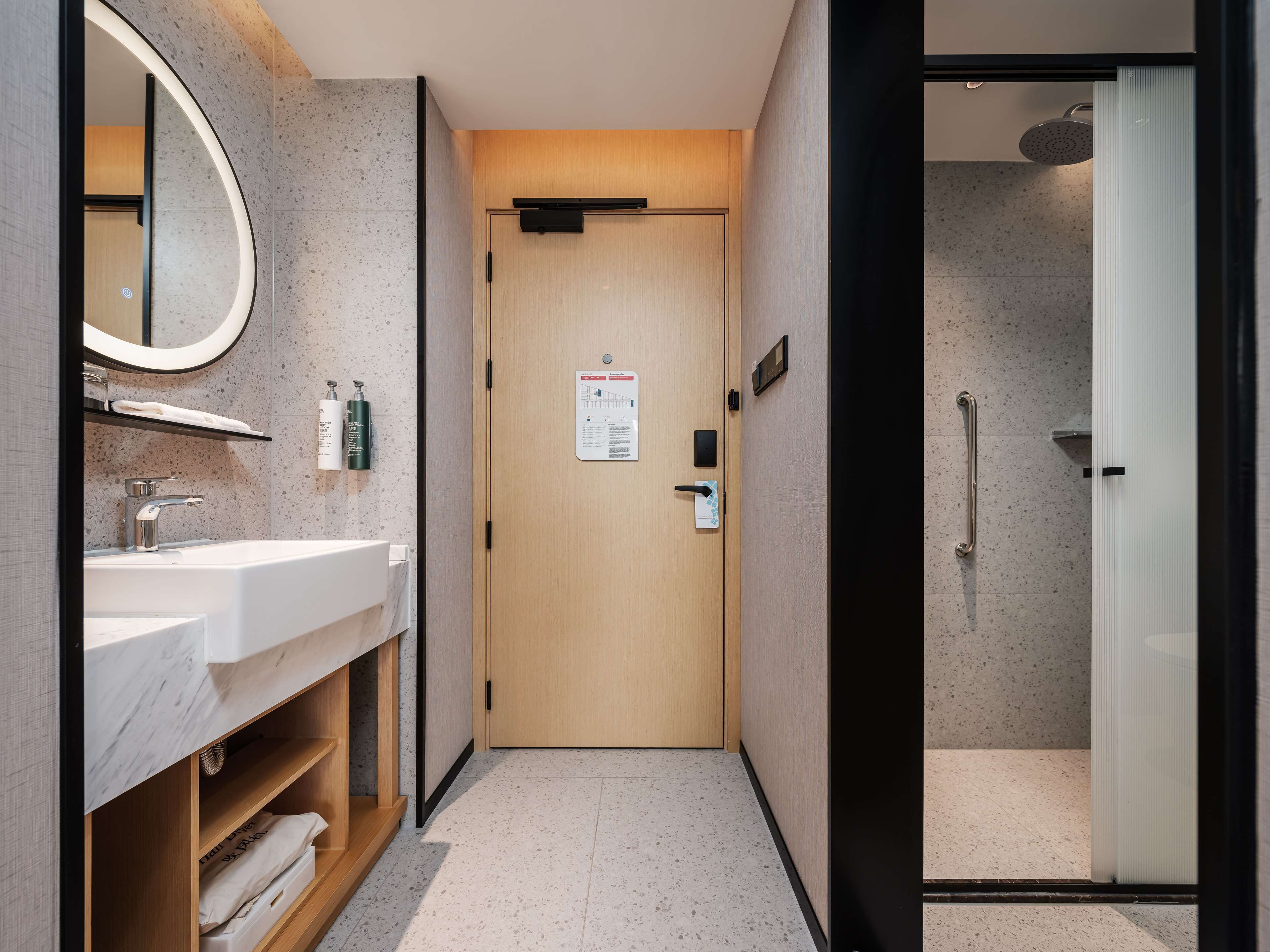 Une salle de bain moderne avec une porte en bois, un lavabo avec un miroir et un espace douche.