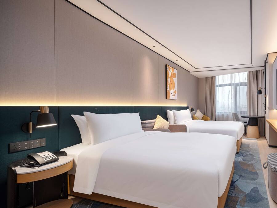 Une chambre d’hôtel avec deux lits, un bureau, une chaise, un téléphone et une lampe.