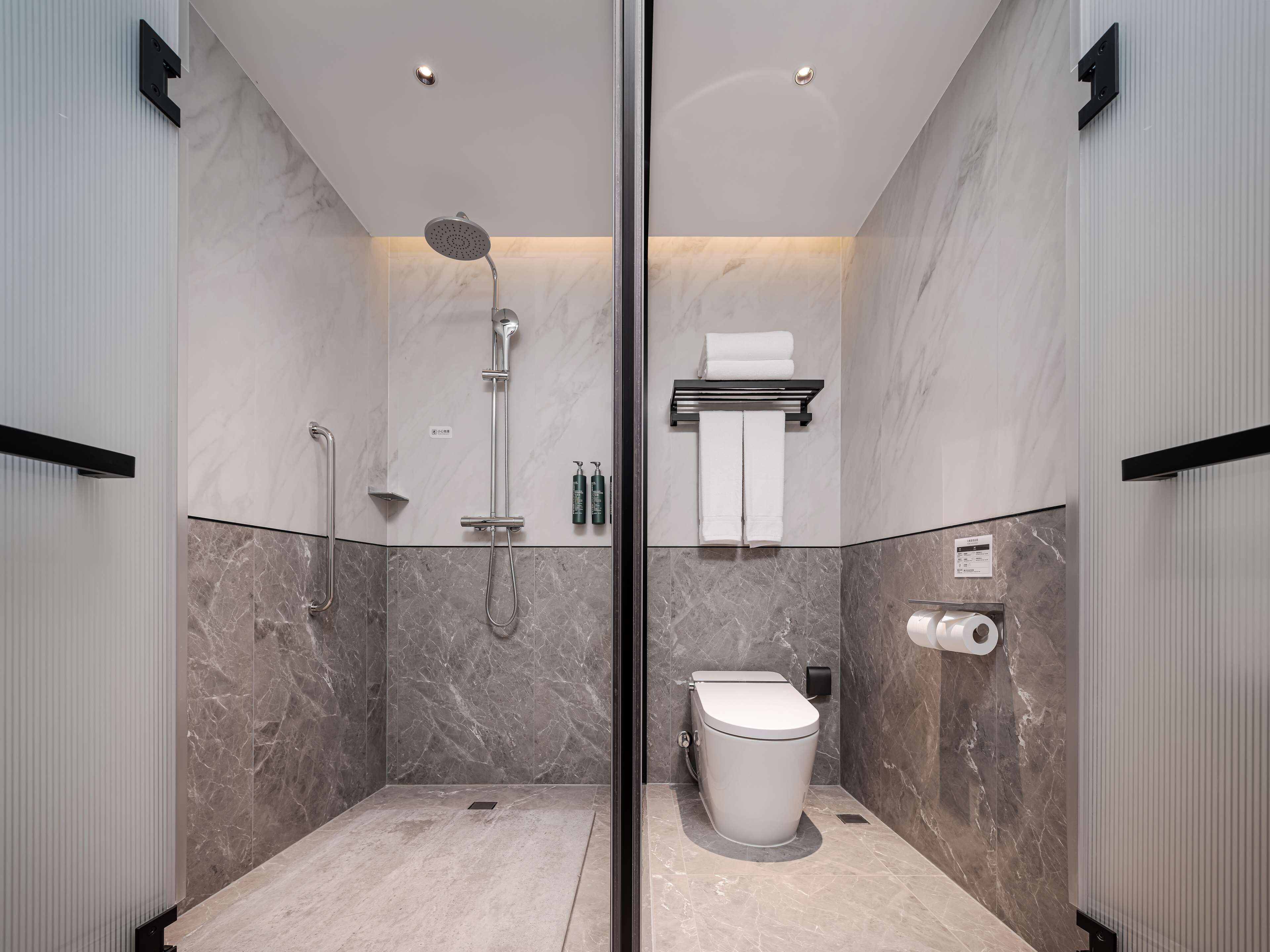 A modern bathroom with a glass partition, a shower, a toilet, and a towel rack.