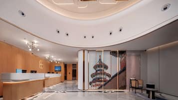 Eine moderne Hotellobby mit einer Rezeption, einem großen digitalen Bildschirm und einer Wandgestaltung mit einem pixeligen Turmdesign.