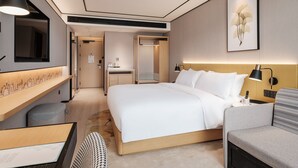 A modern hotel room with a large bed, bedside table, chair, and a desk with a lamp. - Hilton Garden Inn Beijing Temple of Heaven East Gate Station (Beijing)