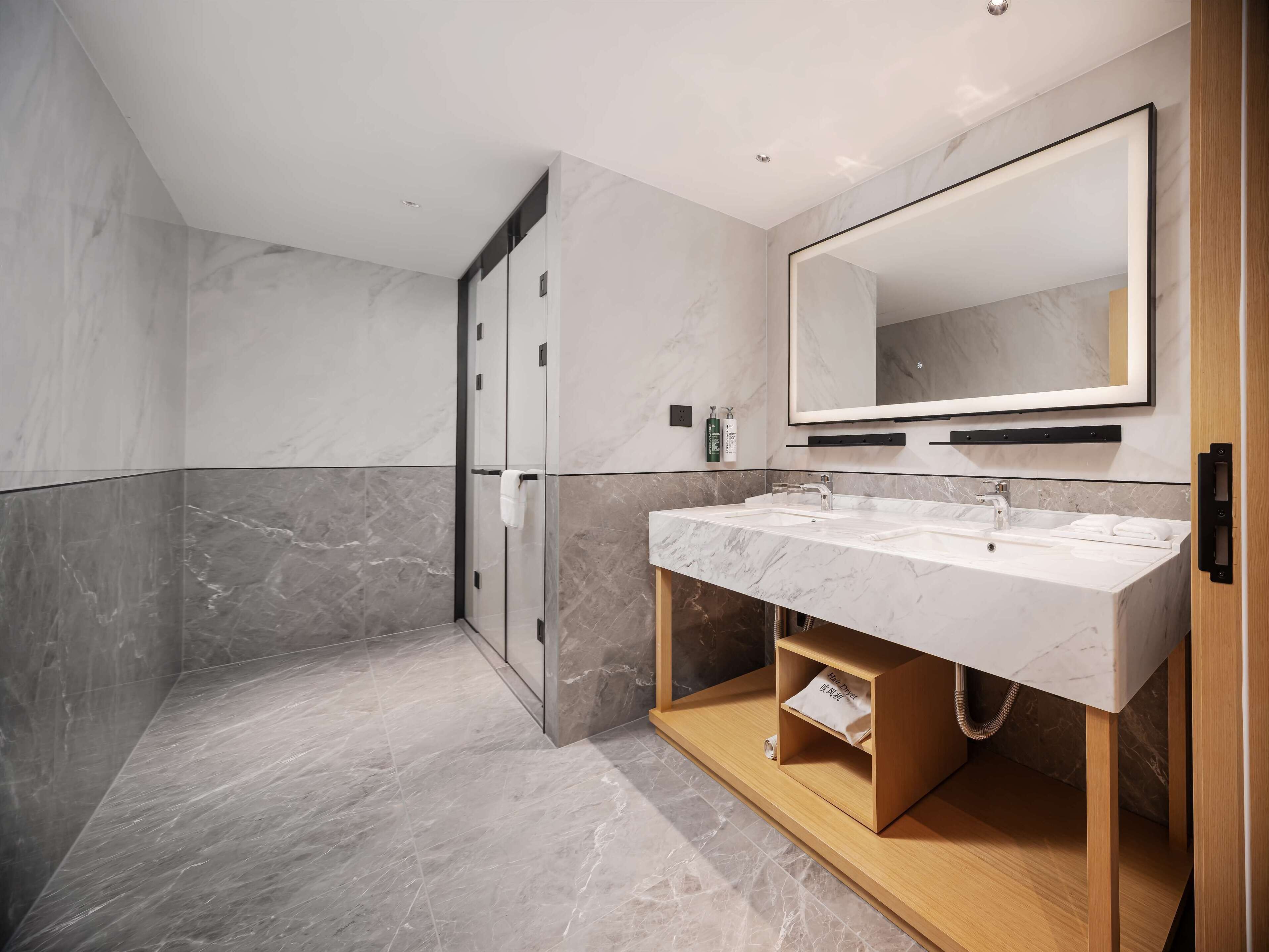 A modern bathroom with a double sink, a large mirror, and a shower enclosure.