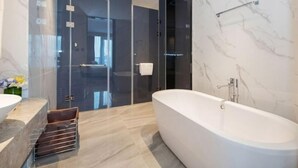 Une salle de bain moderne avec une baignoire sur pieds, une douche à parois de verre et des murs en marbre.