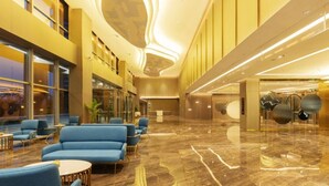 Un hall d’entrée spacieux avec un sol en marbre, des coins salons bleus et un design de plafond moderne.