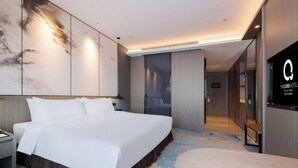 Une chambre d’hôtel moderne, dotée d’un grand lit, d’un bureau et d’une télévision.
