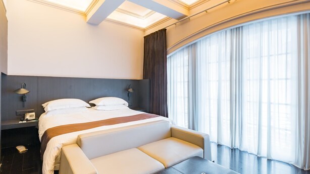 A modern hotel room with a large bed, a seating area, a desk, and a large window with curtains. - Jinjiang Inn Select (Shanghai Nanjing Road Pedestrian Street) (Shanghai)