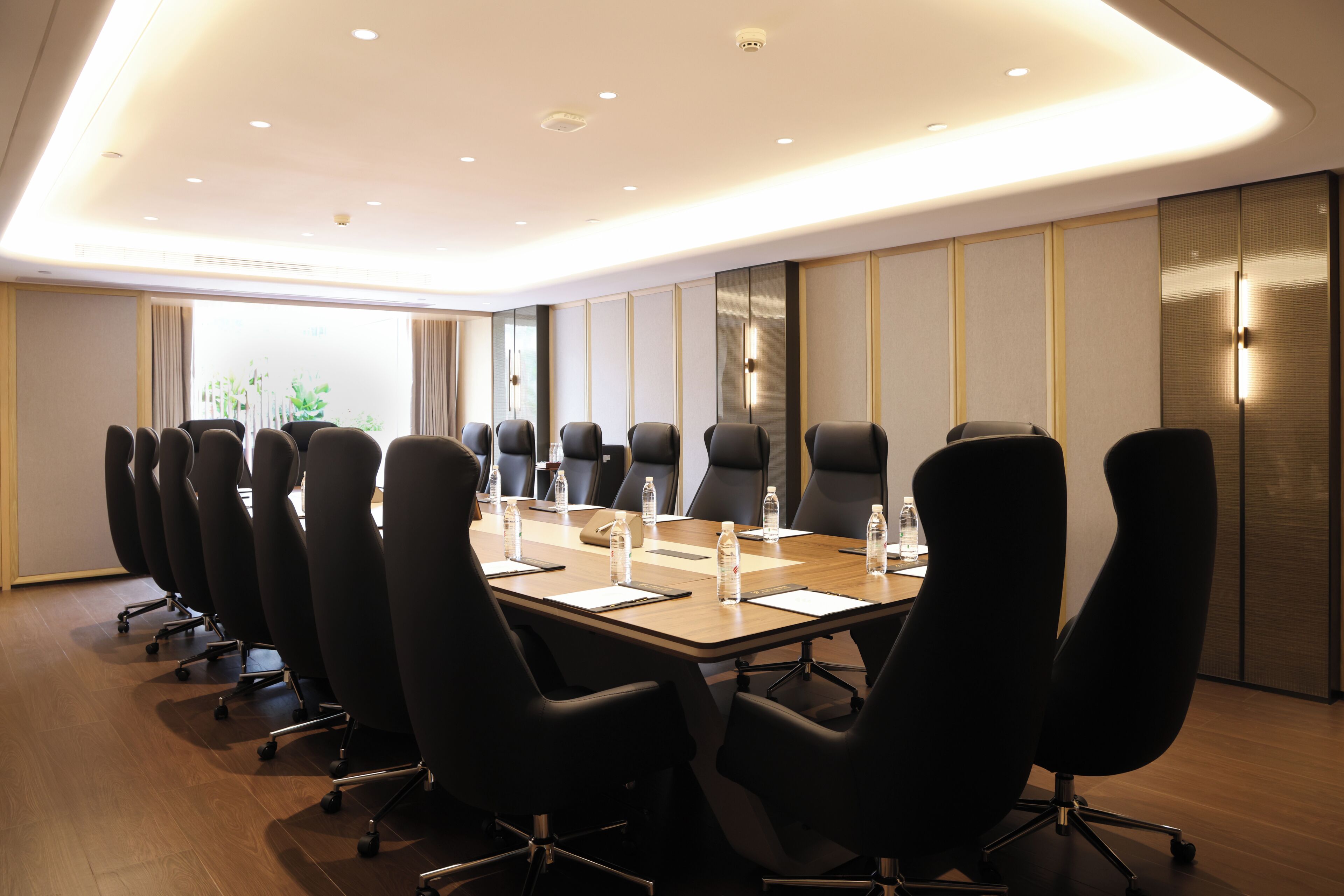 A conference room with a long table, black chairs, and water bottles.