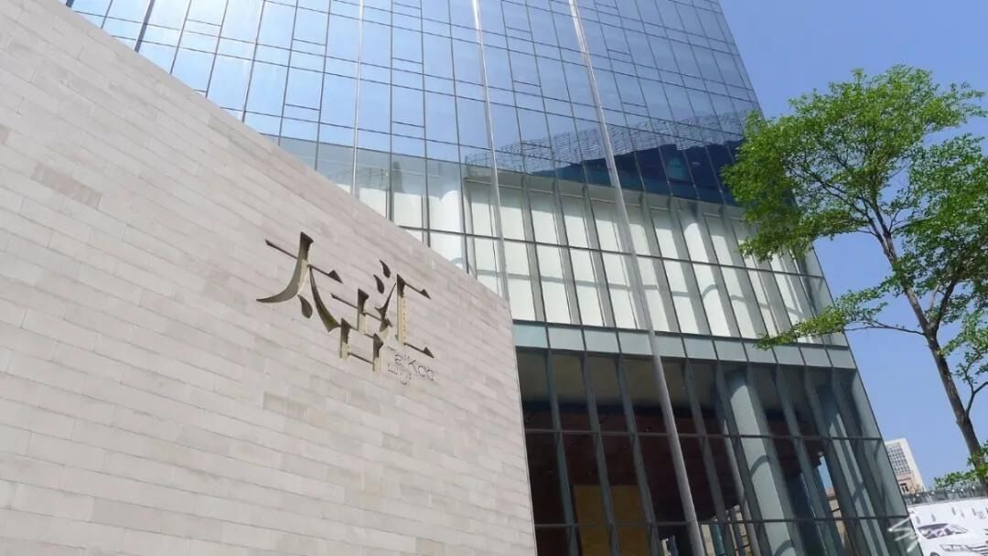 A modern building with a glass facade and a sign with Chinese characters.