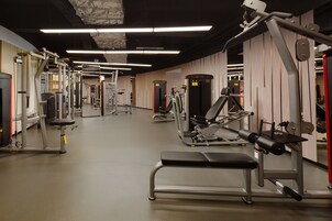 Una palestra con diverse macchine per esercizi, panche e uno specchio lungo la parete.