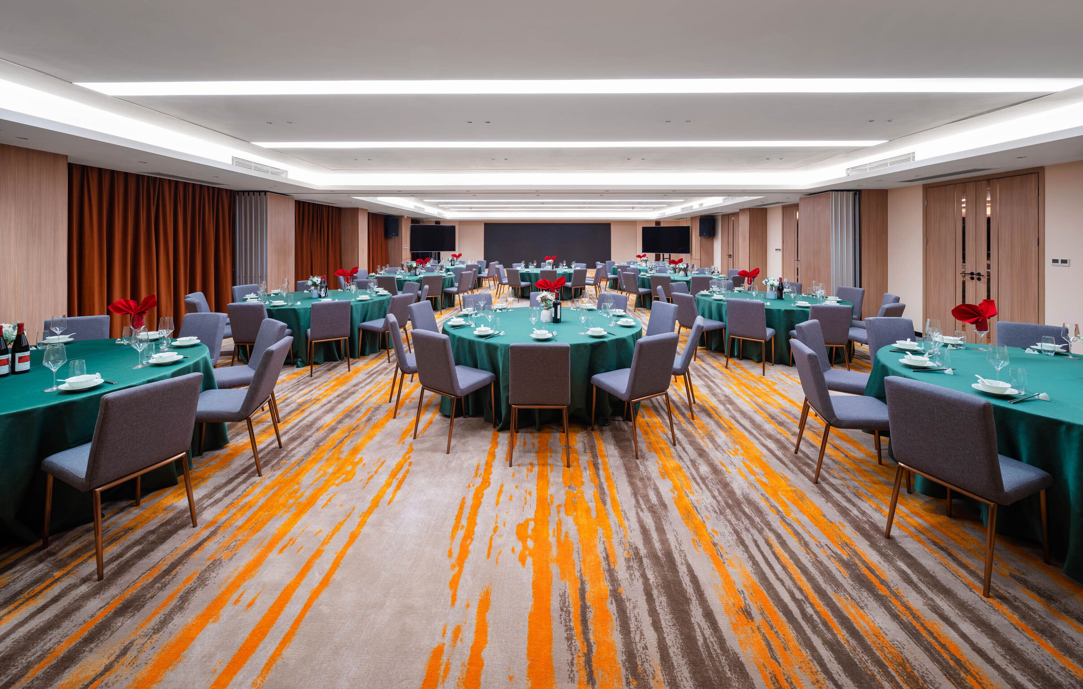 A large conference room with multiple round tables, each set with chairs and table settings.