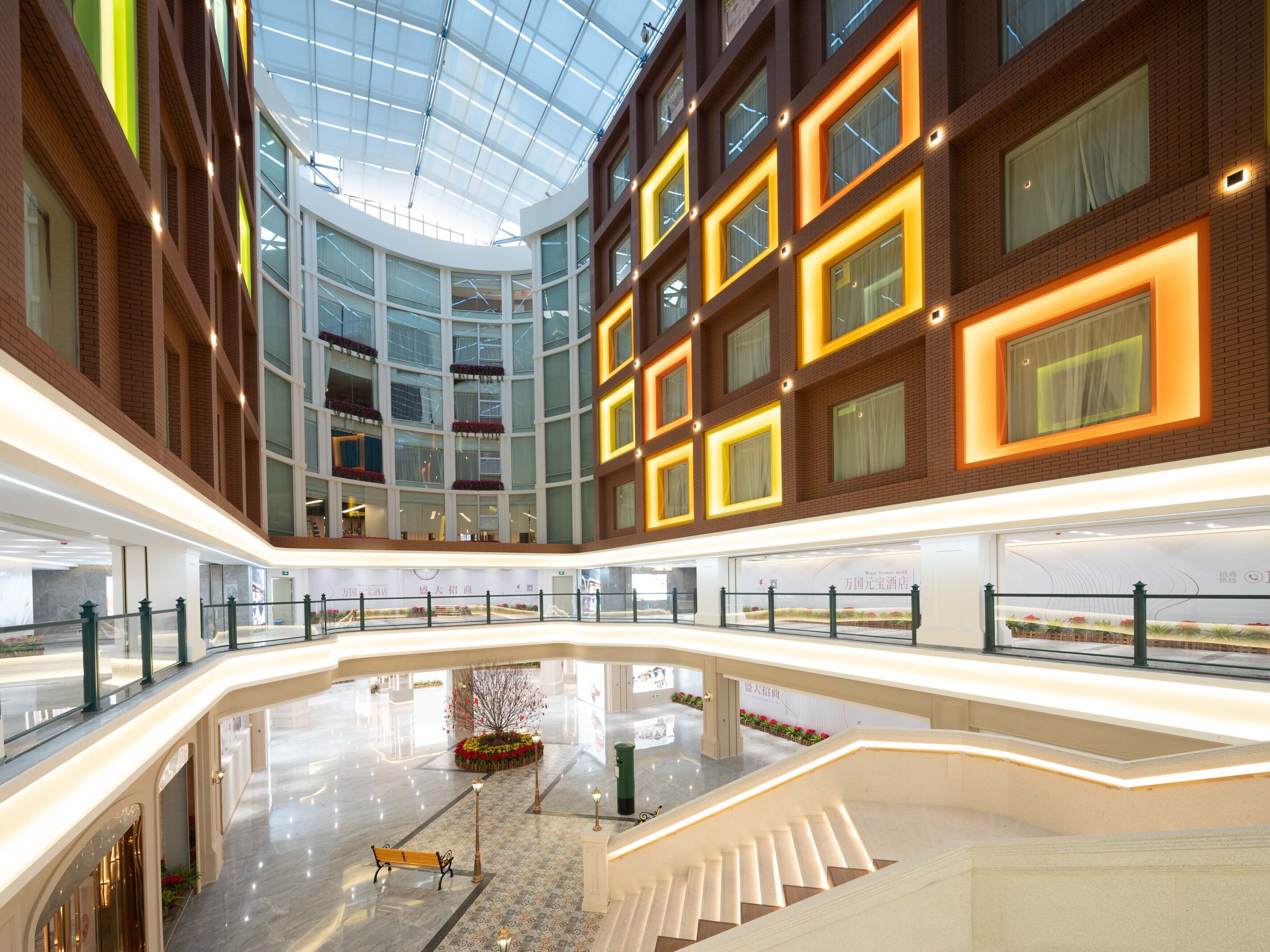 A multi-level atrium with a glass ceiling, modern architecture, and a central garden area.