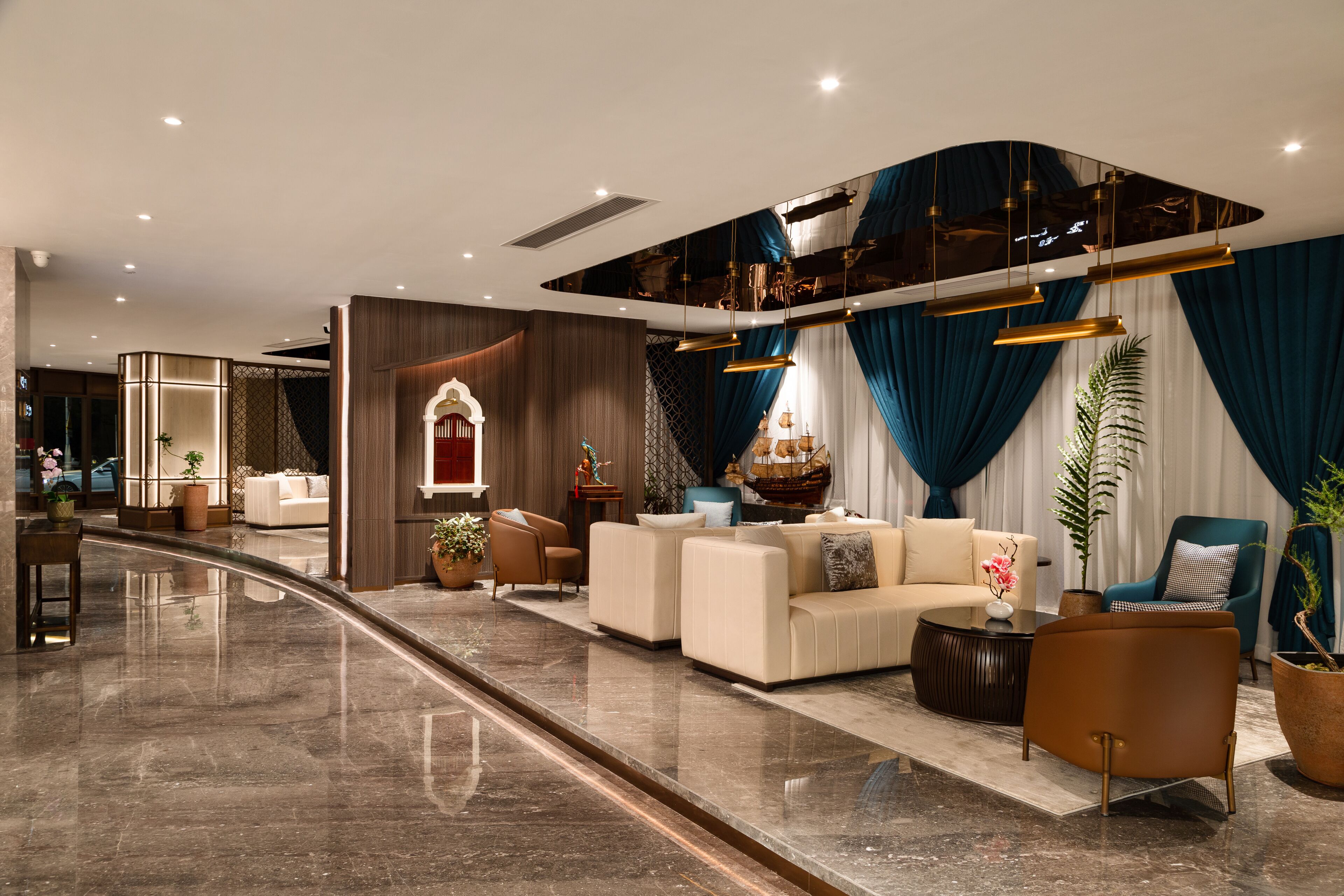 A modern hotel lobby with a curved marble floor, a seating area with sofas and armchairs, and a decorative wall with a ship model.