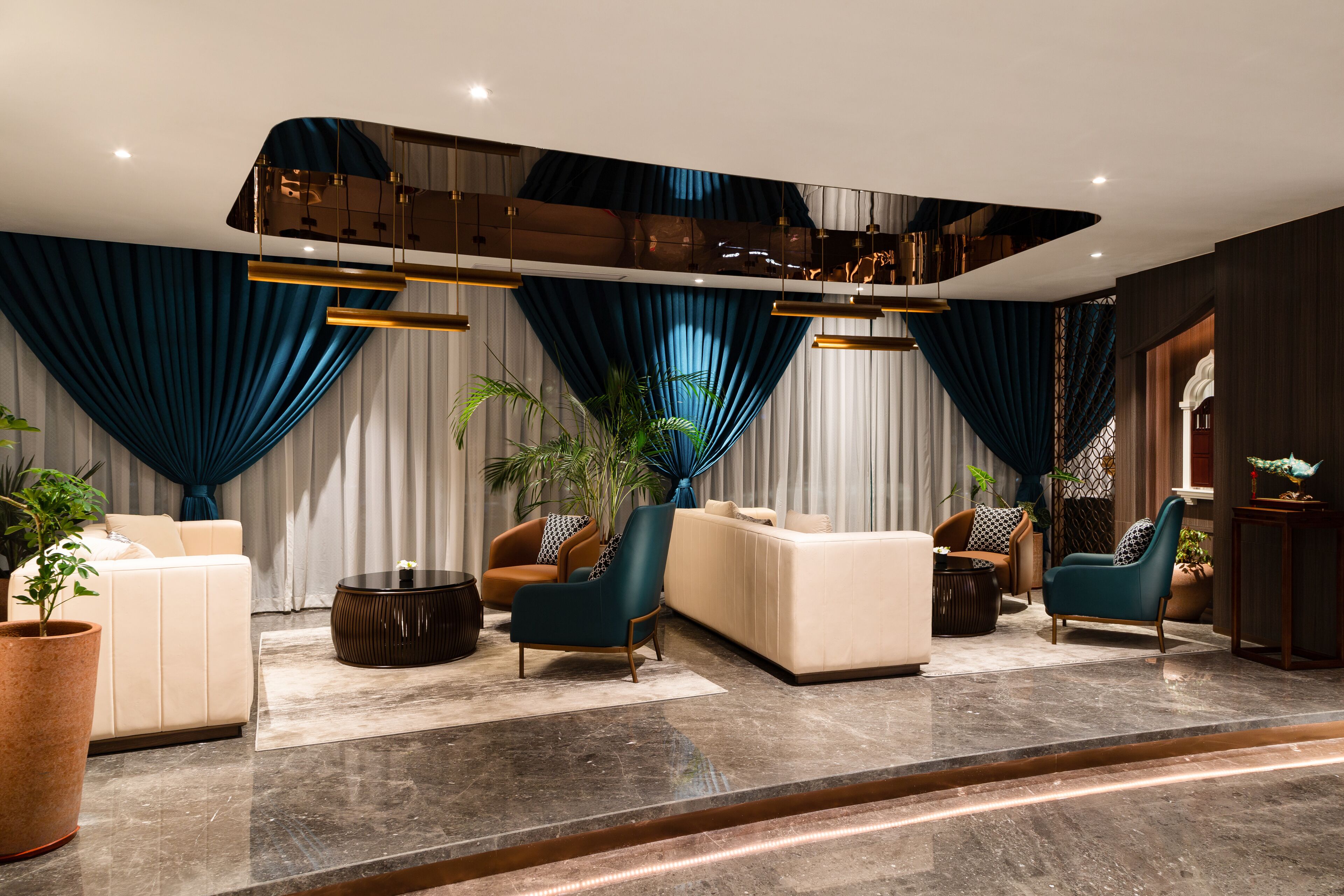 Un salon moderne avec un canapé, des fauteuils, une table basse et une grande plante.