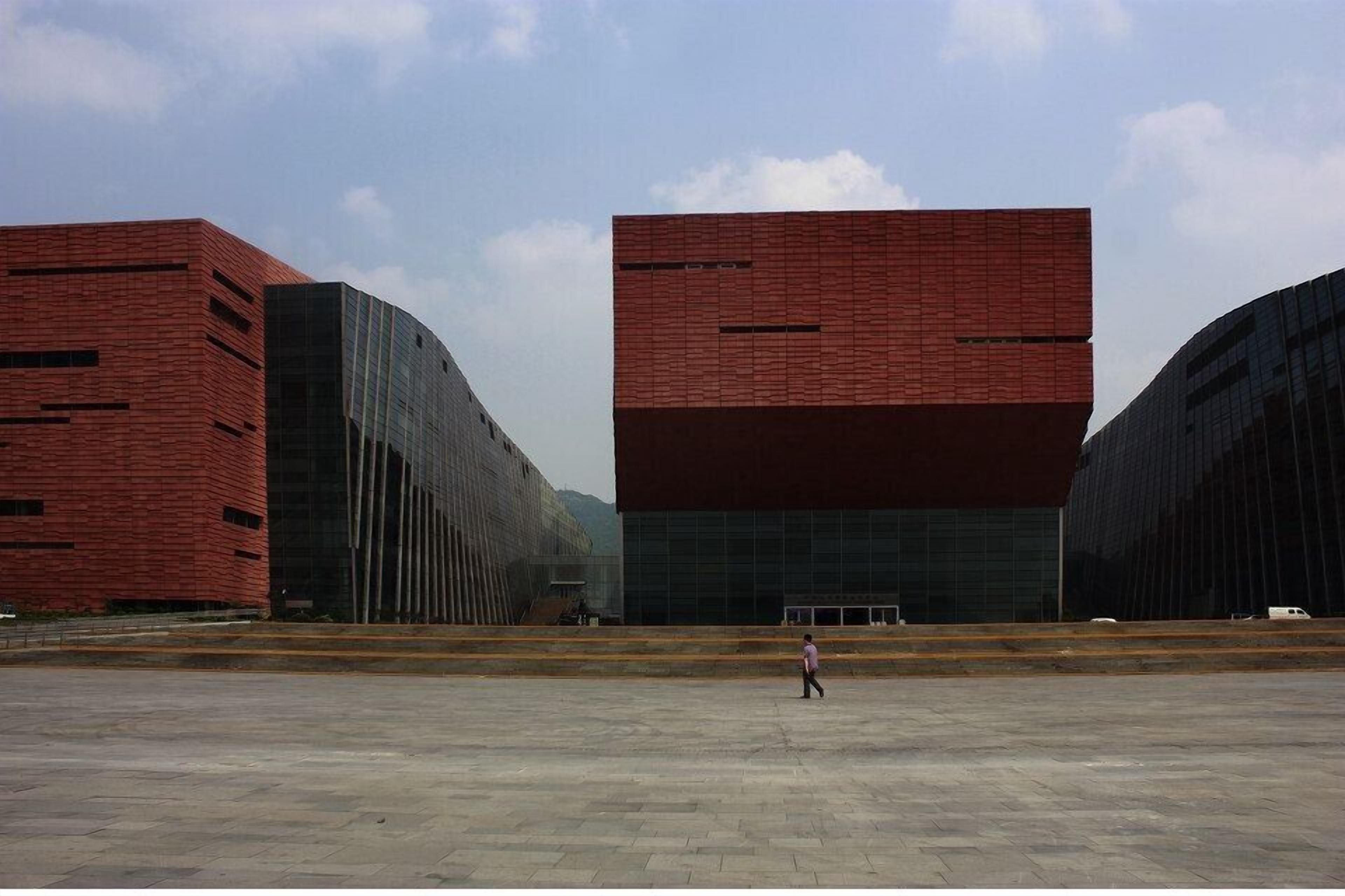 A large, open plaza with modern buildings featuring red brick facades and glass windows.