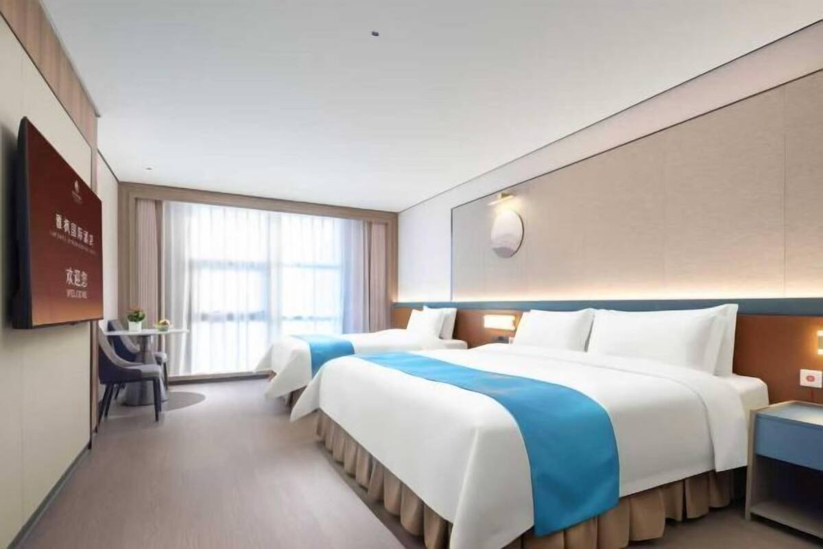 Een hotelkamer met twee bedden, een bureau, een stoel en een groot raam.
