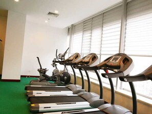 Várias esteiras num espaço com janelas amplas e carpete verde.