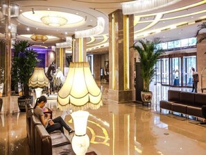 A spacious lobby with a high ceiling, large chandeliers, and a seating area with a sofa and armchairs. - Inner Mongolia Grand Hotel (Beijing)