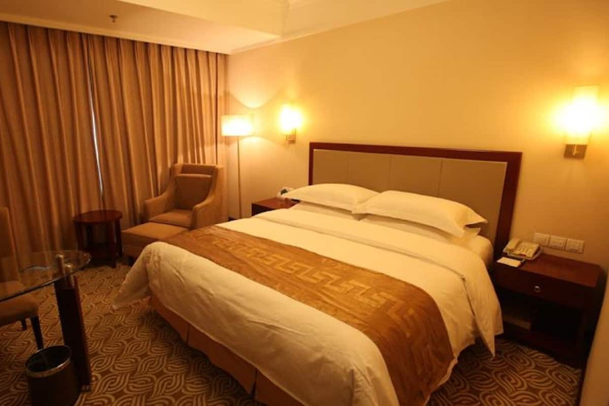Une chambre d’hôtel avec un lit, une chaise, une petite table et une lampe.