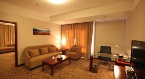 A hotel room with a sofa, armchair, coffee table, TV, and a painting on the wall. - Inner Mongolia Grand Hotel (Beijing)