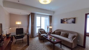 A hotel room with a sofa, armchair, desk, and a large window with curtains. - Inner Mongolia Grand Hotel (Beijing)