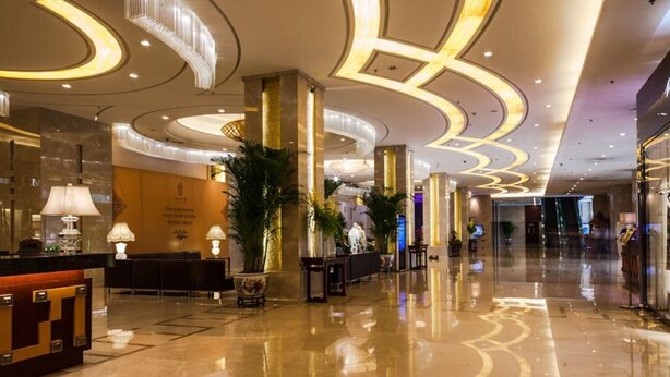 A hotel lobby with a reception desk, large columns, and a modern ceiling design. - Inner Mongolia Grand Hotel (Beijing)