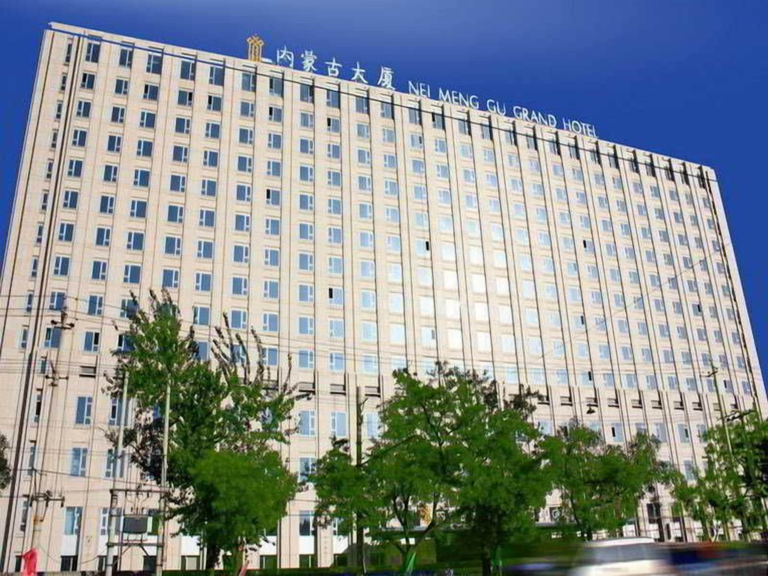 Un hotel de varios pisos con una fachada uniforme, numerosas ventanas y un cielo despejado.
