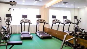 Un gimnasio con cintas de correr, elípticas y pesas sueltas.