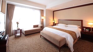A hotel room with a large bed, a sofa, a small table, and a TV. - Inner Mongolia Grand Hotel (Beijing)
