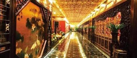A corridor with a tiled floor, a patterned ceiling, and traditional wall decorations.