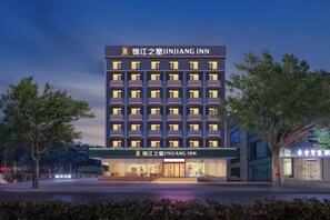 A multi-story hotel with a modern facade, multiple balconies, and a well-lit entrance.