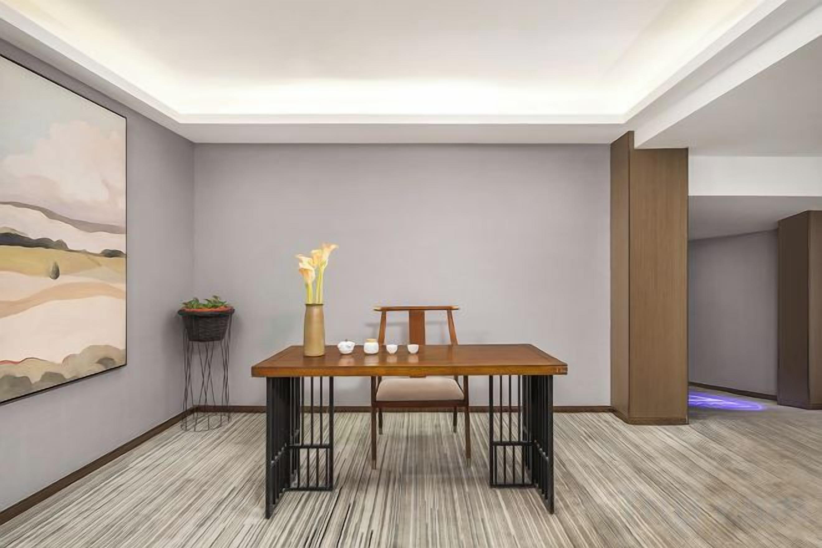 Un comedor con una mesa, sillas, un florero con flores y un cuadro en la pared.