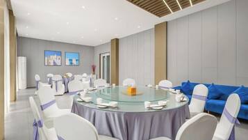 A conference room with a round table, white chairs with purple sashes, and a blue sofa.