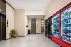 A hallway with vending machines, a potted plant, and a door leading to another room. - Jinjiang Zhixing (Jiaozuo Jianshe Road Railway Station Shop) (Jiaozuo)