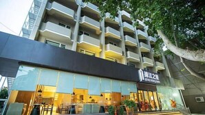 Un hôtel moderne doté d’une façade en verre, de nombreux balcons et d’un espace restaurant bien visible.