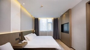 Une chambre d’hôtel avec un grand lit, des tables de chevet, une télévision et une fenêtre avec des rideaux.