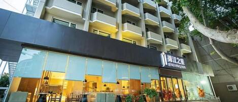 Un hotel con fachada moderna, entrada visible y escalera que conduce a ella.