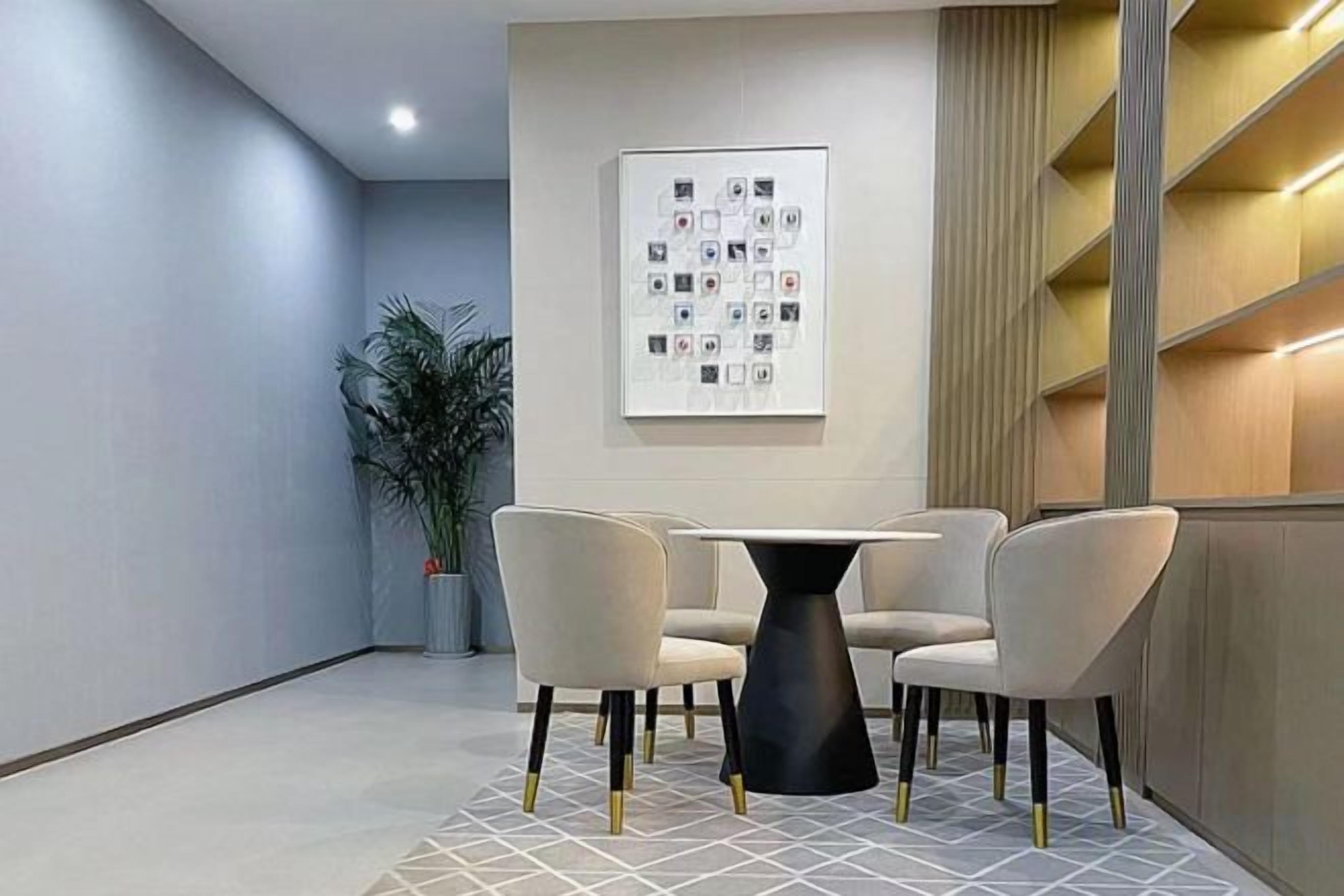 Un comedor moderno con una mesa redonda y cuatro sillas, una planta en maceta y una obra de arte colgada en la pared.