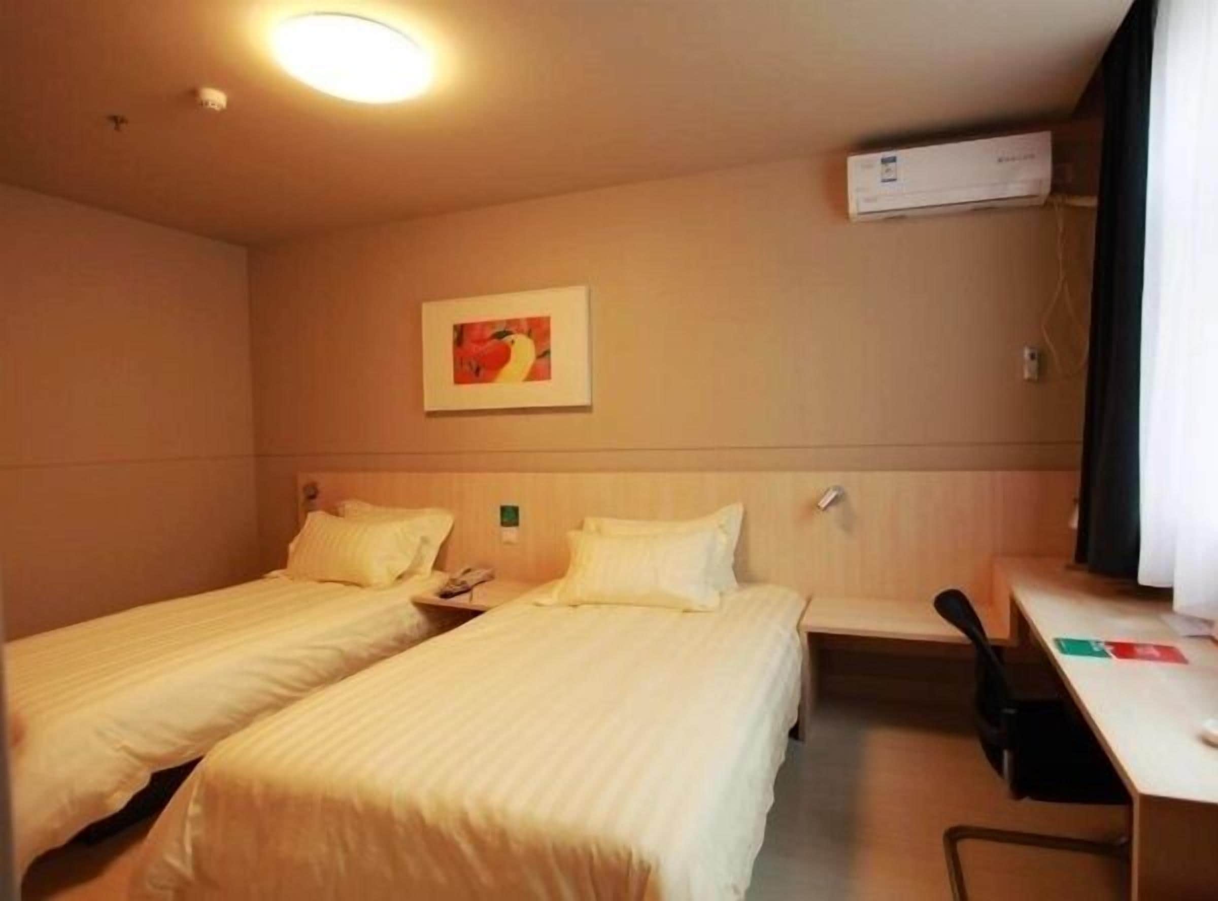 A hotel room with two single beds, a desk, and a chair.