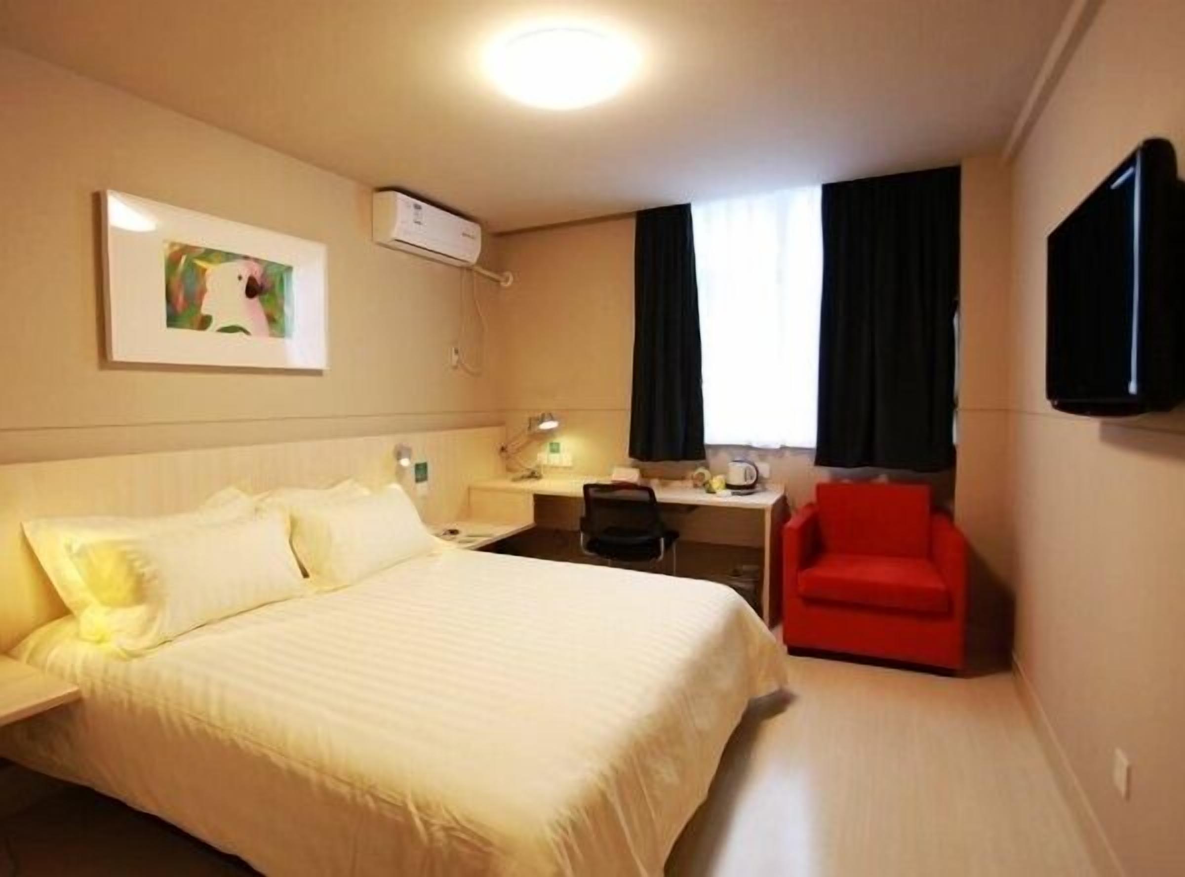Een hotelkamer met een bed, een bureau, een stoel, een flatscreen-televisie en een schilderij aan de muur.