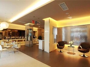 Un hall d’hôtel moderne comprenant un comptoir d’accueil, un espace salon et une grande fenêtre offrant une vue agréable.