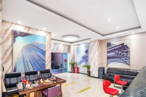A hotel lobby with a marble reception desk, red chairs, and large wall art depicting a modern building. - Jilv Boutique Hotel (Guangzhou Shangxiajiu Pedestrian Street Xichang Subway Station) (GUANGZHOU)
