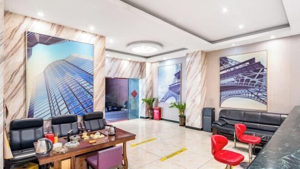 A hotel lobby with a marble wall, a dining area with a table and chairs, and a seating area with red chairs. - Jilv Boutique Hotel (Guangzhou Shangxiajiu Pedestrian Street Xichang Subway Station) (GUANGZHOU)