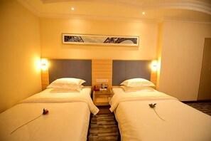 Une chambre d’hôtel avec deux lits, une œuvre d’art au niveau de la tête de lit, des lampes de chevet et un sol recouvert de moquette.