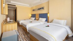 A hotel room with three beds, a desk with a laptop, a mirror, and a framed picture on the wall. - Jilv Boutique Hotel (Guangzhou Shangxiajiu Pedestrian Street Xichang Subway Station) (GUANGZHOU)
