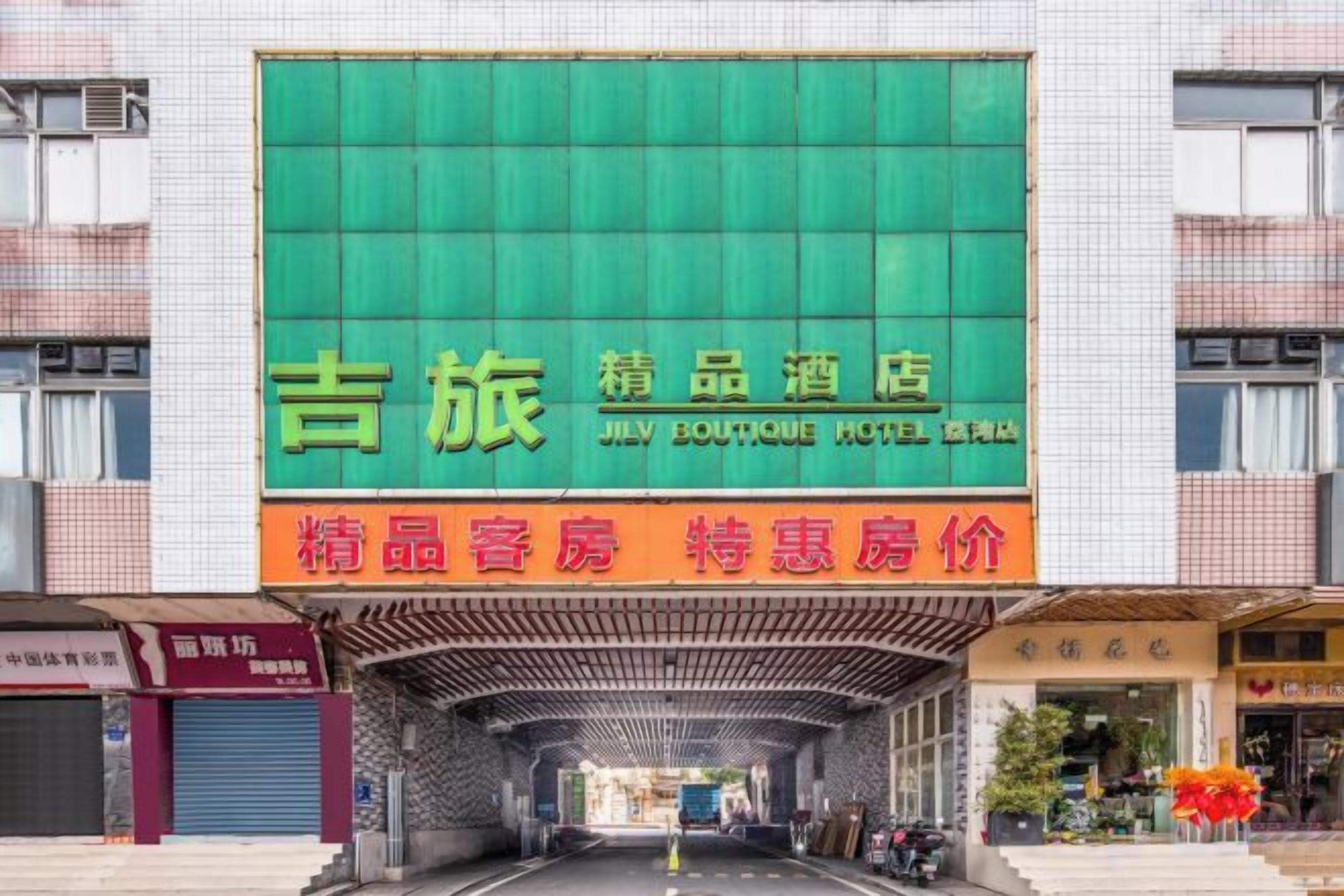 A hotel entrance with a green signboard and a covered walkway.