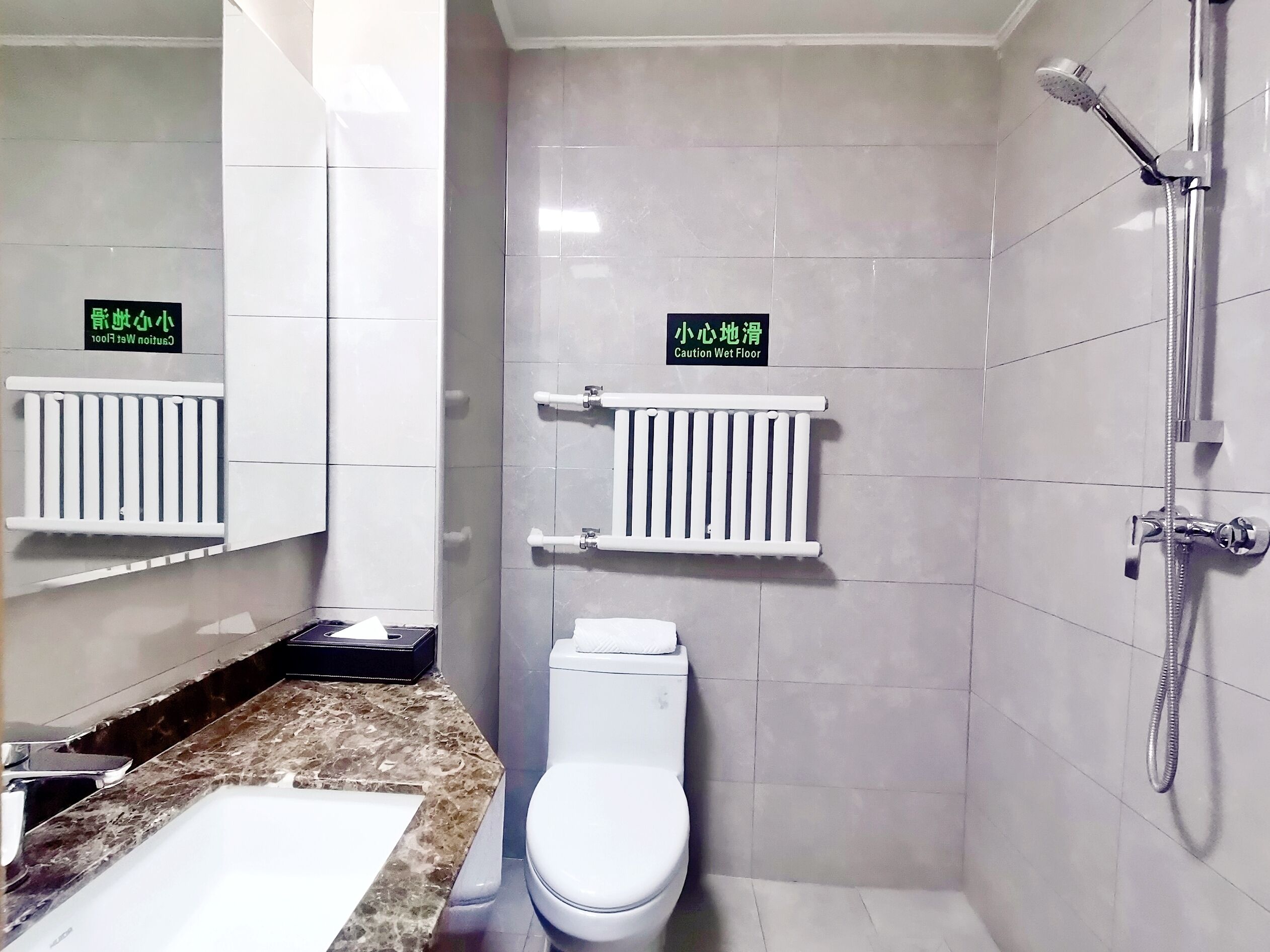 A bathroom with a white toilet, a sink, a shower, and two towel racks.