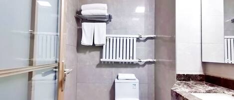 A small, modern bathroom with a toilet, a towel rack, and a shower area.