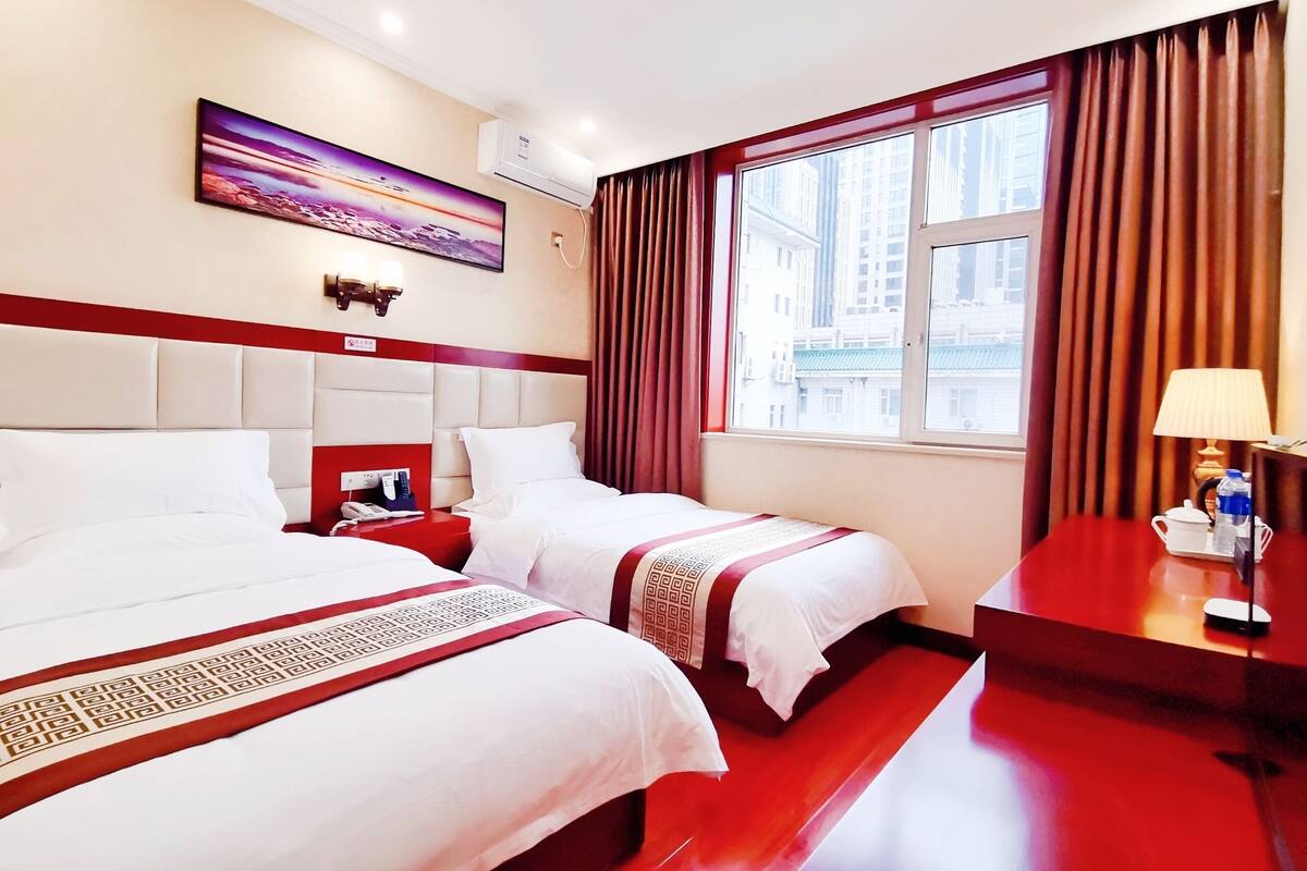 Une chambre d’hôtel avec deux lits, un bureau, une lampe et un tableau au mur.