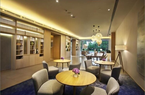 A modern hotel lobby with a long reception desk, comfortable seating areas, and a large window offering a view of the outdoors. - Ji Hotel (Beijing)